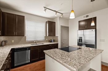 A kitchen with granite countertops and a stainless steel refrigerator.at Cypress at Lewisville Apartment Homes, Lewisville, 75067